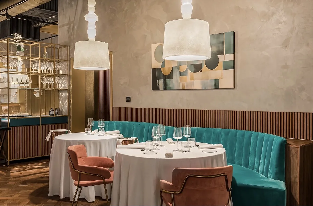 Sala ristorante con tavoli rotondi apparecchiati con tovaglie bianche